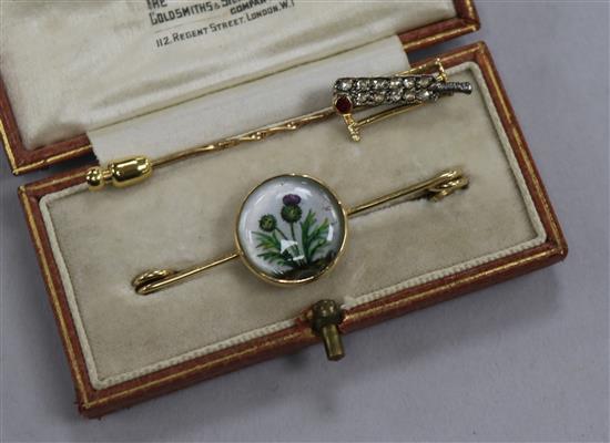 An early 20th century novelty yellow metal, diamond and gem set cricket bat and stumps stick pin and a bar brooch with thistle.